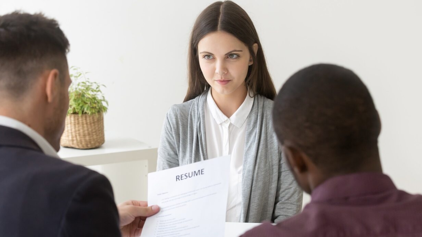 Multiracial hr reading resume of millennial applicant, confident graduate girl starts career being interviewed by recruiters for vacant position at hiring negotiations, employment, first job concept