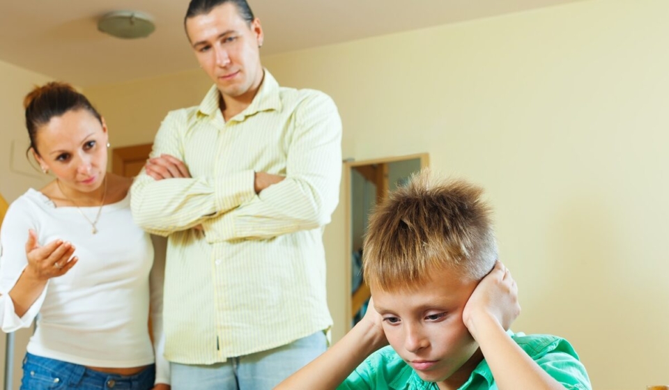 Parents berates her teenage child in interior. Focus on boy only